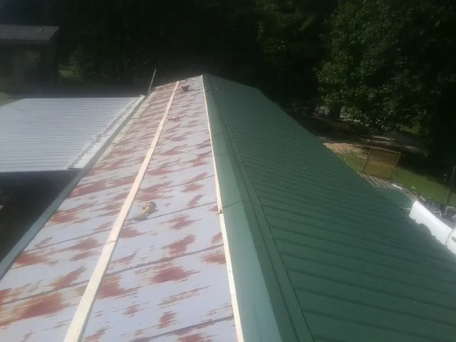 Old rusted panels beside newly installed green metal roofing — Wind Damage Roof Repair by Roofing Brothers in Opa Locka