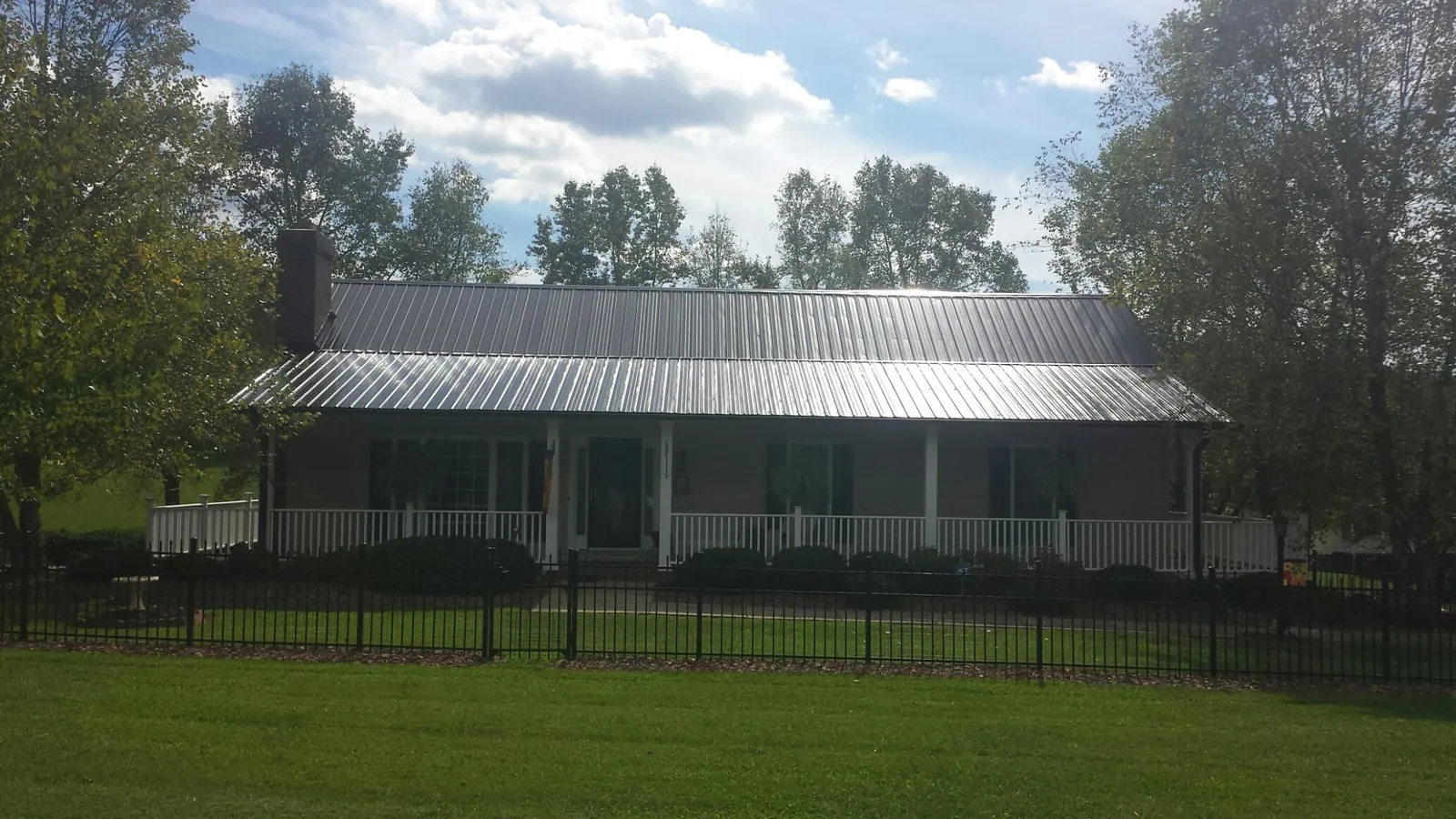 Gray metal roof on a brick ranch with a full width front porch — Gutter Guard Installation work by our crew in Opa Locka