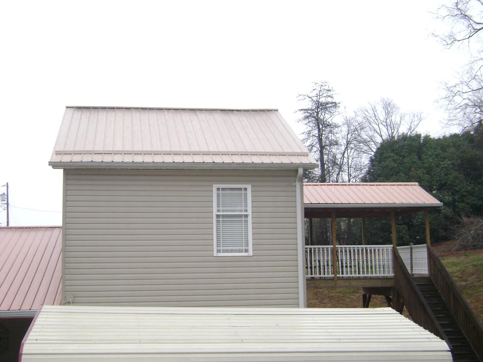Tan metal roofs on a two story addition and attached porch, from a Roof Replacement job in Opa Locka